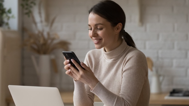 Woman texting while on computer