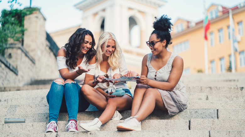 Three girls on stairs holding map