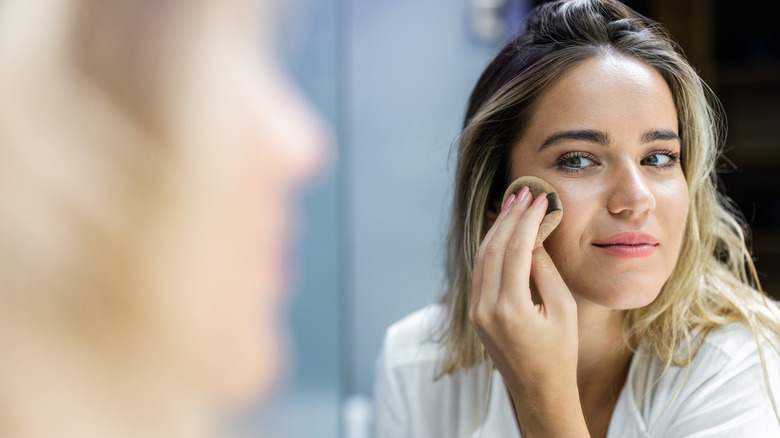 Woman applying highlighter on cheeks