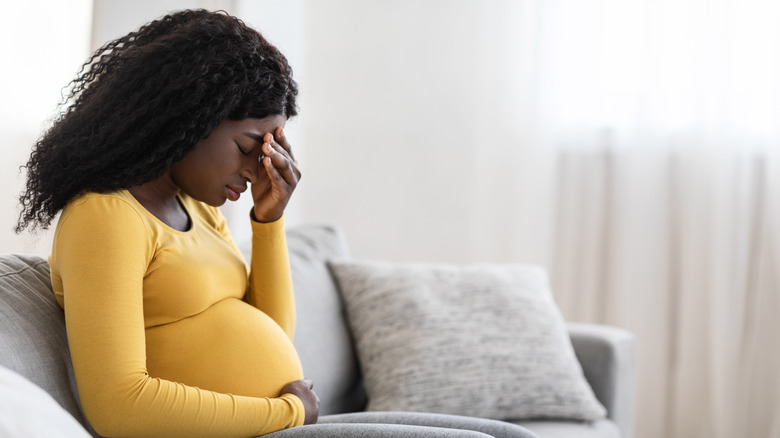 Pregnant woman holding her head