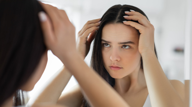 A woman examining her scalp