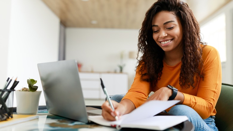 Woman takes notes from laptop screen