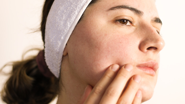 Model with rosacea examining face