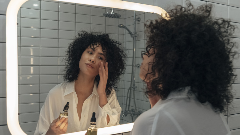 Model applying product to face in mirror