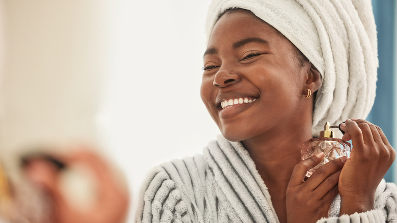 Woman spraying perfume onto neck