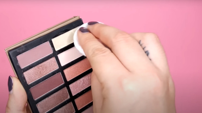 Woman dabbing makeup palette with alcohol