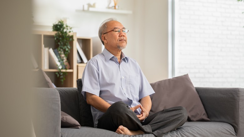 man with glasses meditating on couch