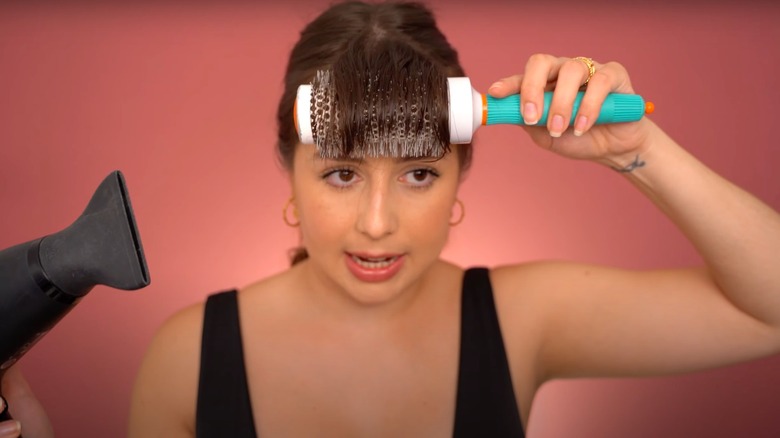 Woman styling bangs with blowdryer