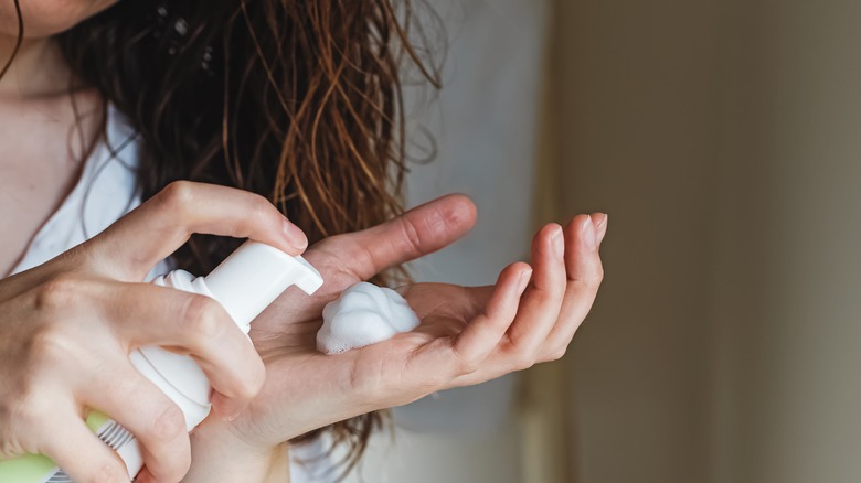 Woman dispensing mousse into hand