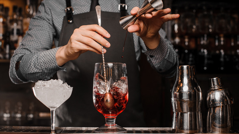 Bartender building a drink in a mixing glass