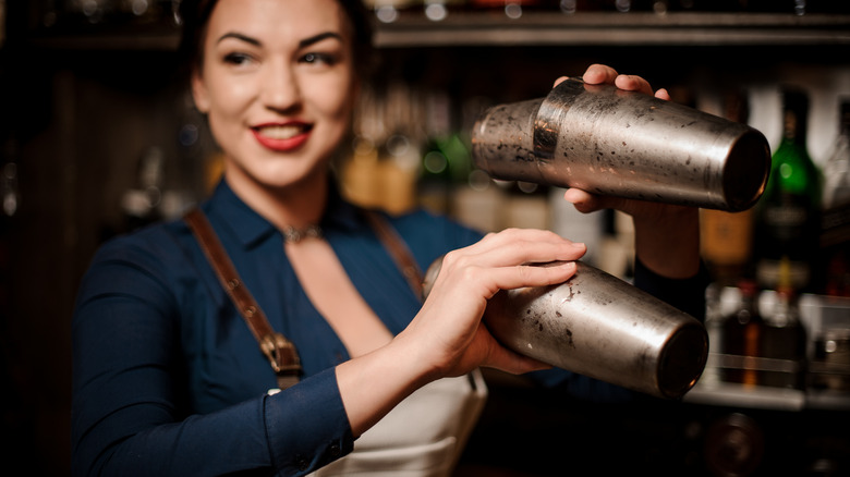 Female bartender shakes up two cocktails