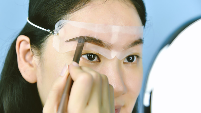 Woman using eyebrow stencils