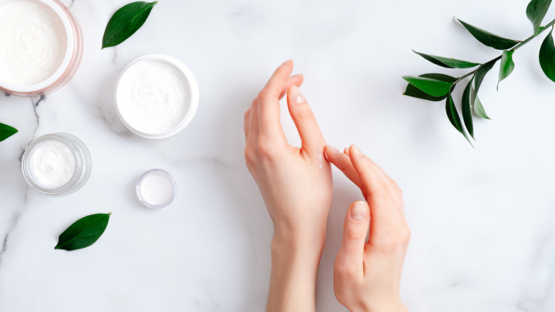 hands next to jars of cream moisturizer