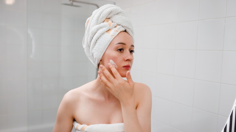 woman applying cream on face