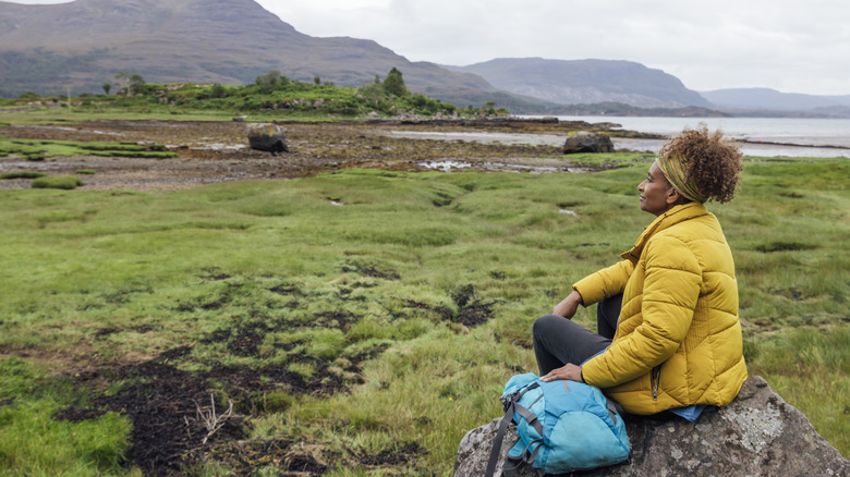 Grounded woman sits on boulder