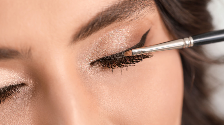 woman applying winged eyeliner