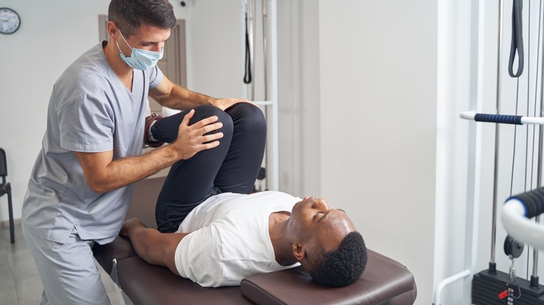 Doctor helping injured man stretch