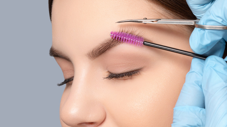 Woman having her brows trimmed with a brow brush and a spoolie