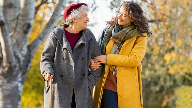 young woman helping senior woman walk