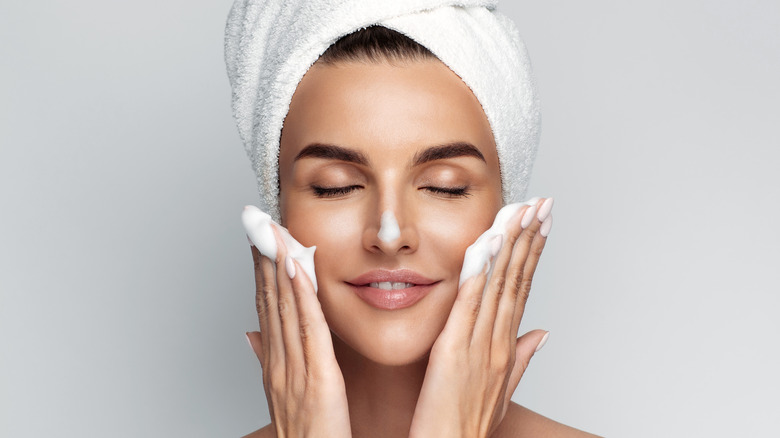 woman applying foam cleanser on face