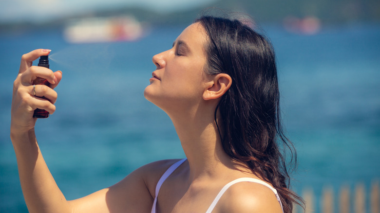 woman applying sunscreen spray