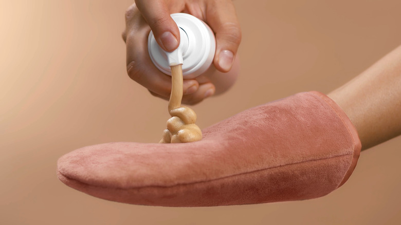 person applying self-tanner to glove