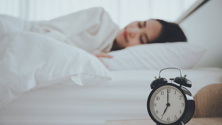 woman sleeping by alarm clock