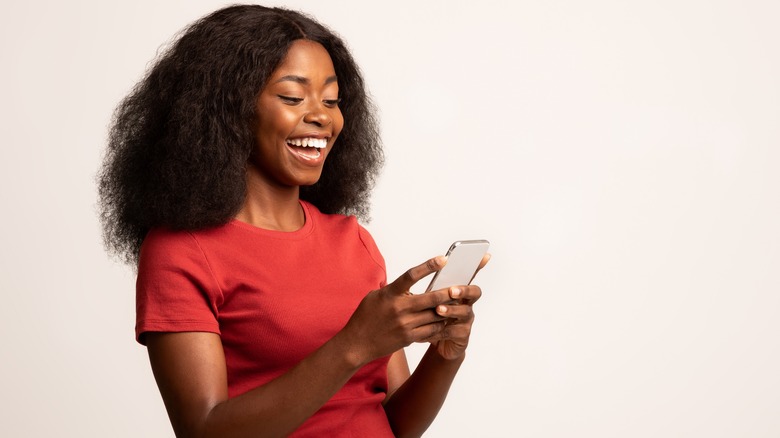Black woman smiling at cell phone