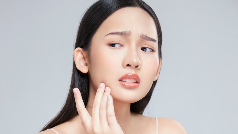 woman touching skin looking worried