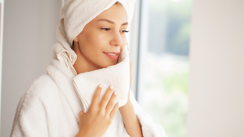 Woman wearing robe using washcloth