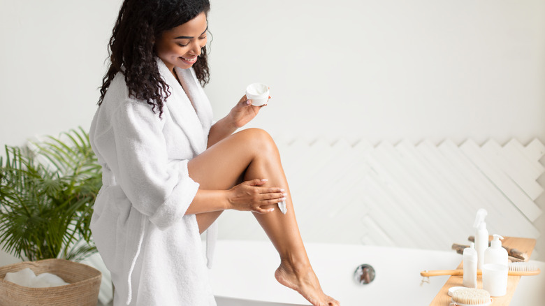 Woman shaving legs in bathtub