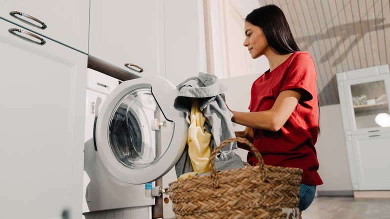 Woman taking clean laundry from dryer
