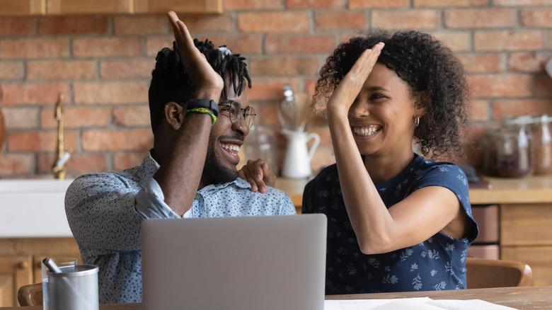 Couple high-five at laptop.