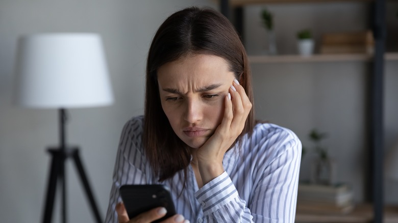 Woman looking at phone stressed.