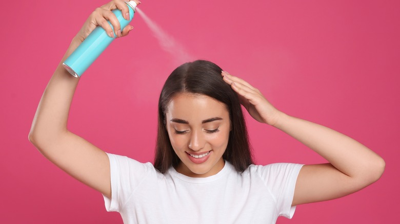 woman spraying on dry shampoo