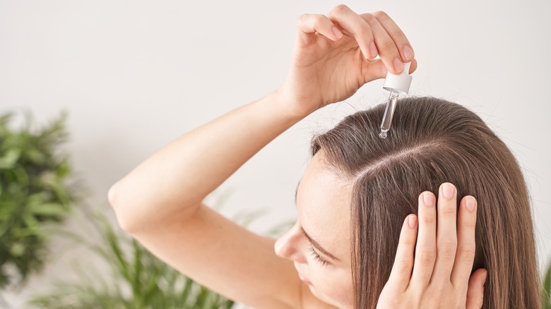 woman applying serum to hair