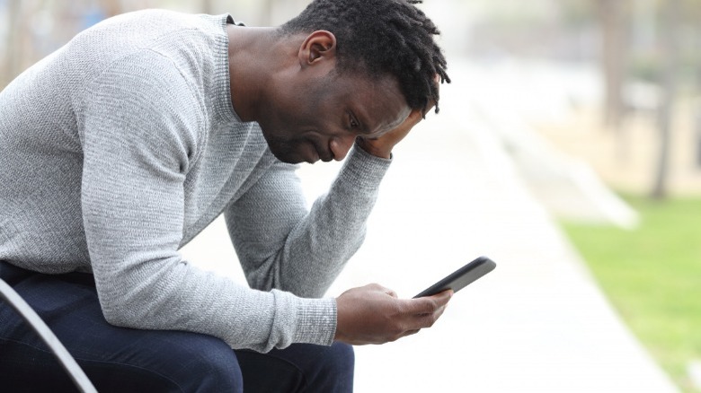 Sad man looking at phone