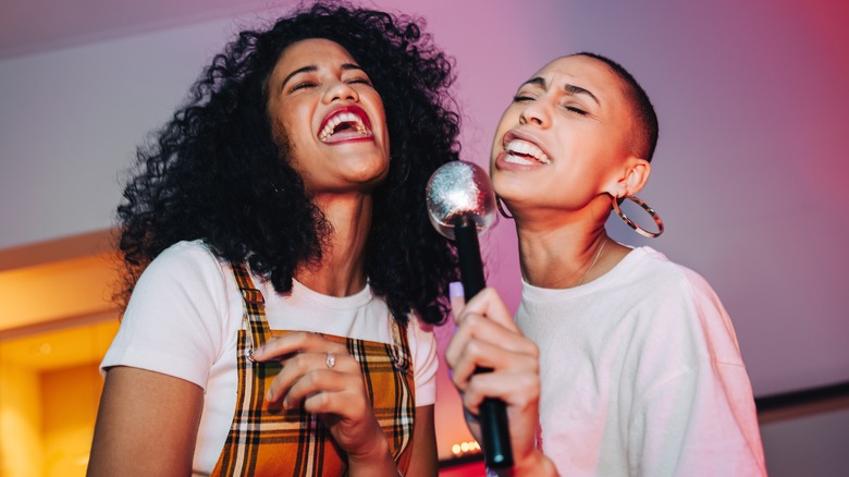 two women singing into microphone