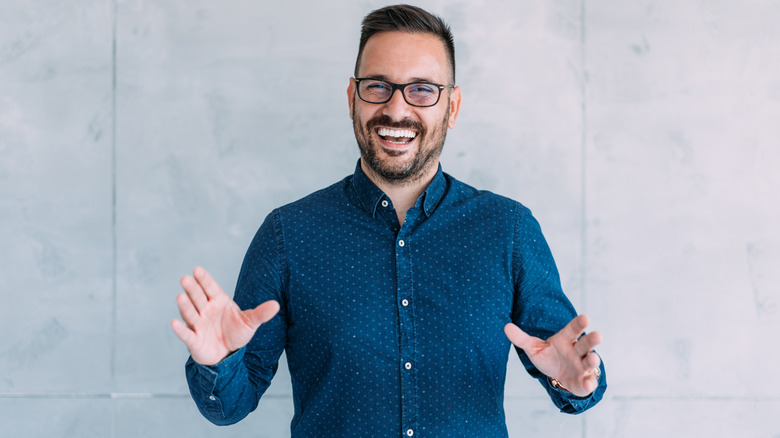 Man smiling with arms raised