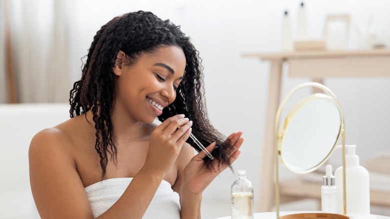 Curly-haired woman applying hair oil