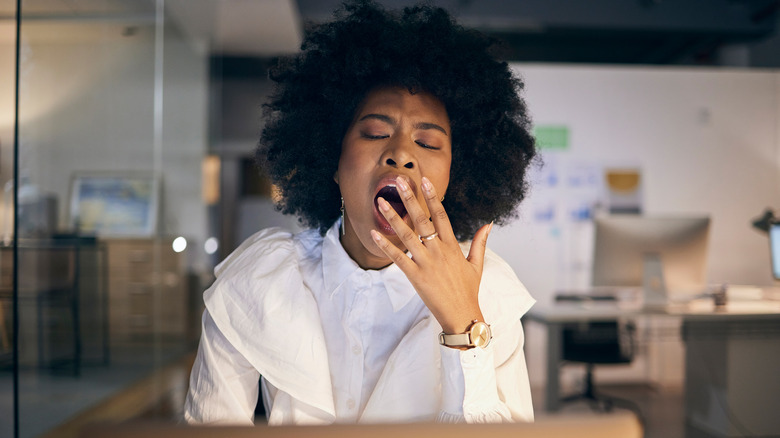 A woman covering her mouth while yawning