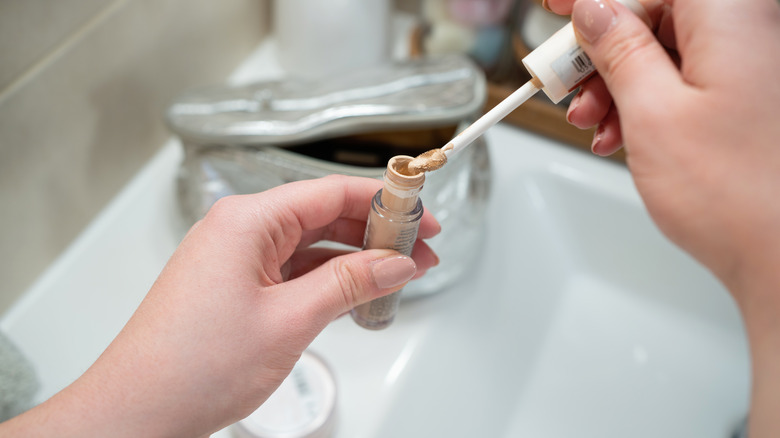 A woman holding concealer