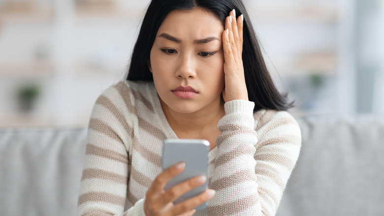 upset woman looking at smartphone