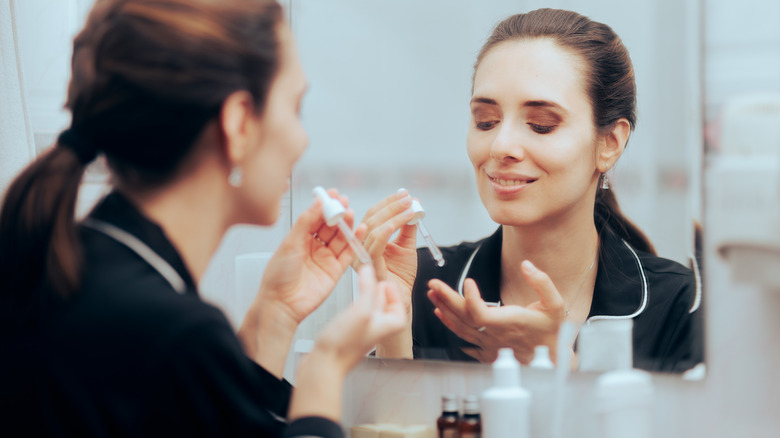 Woman applying retinol to the face.