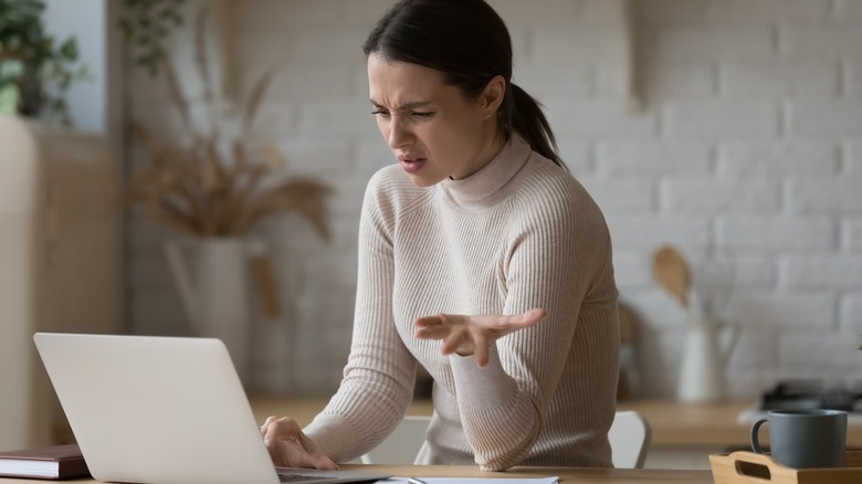 woman looking at laptop confused or fed up