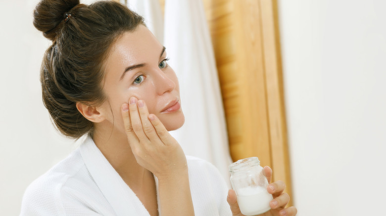 Woman applying moisturizer to face