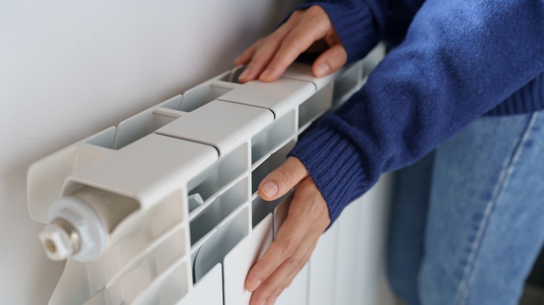 Woman putting hand on heater