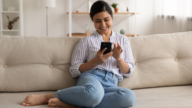 woman sending text on couch