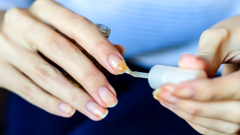 Woman's hands applying clear nail polish