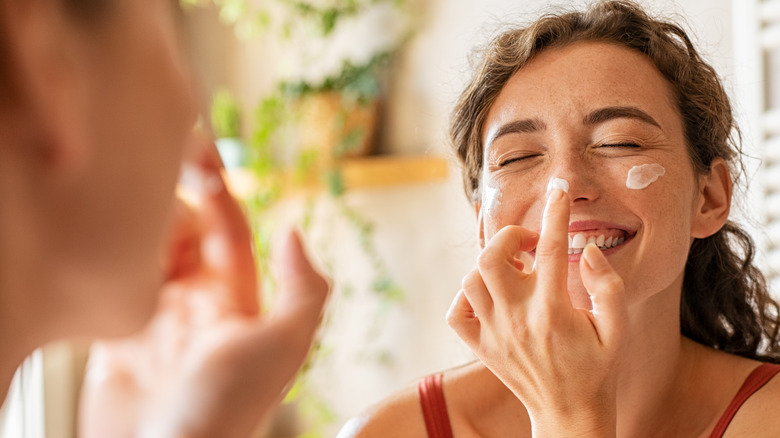 Smiling woman applying moisturizer